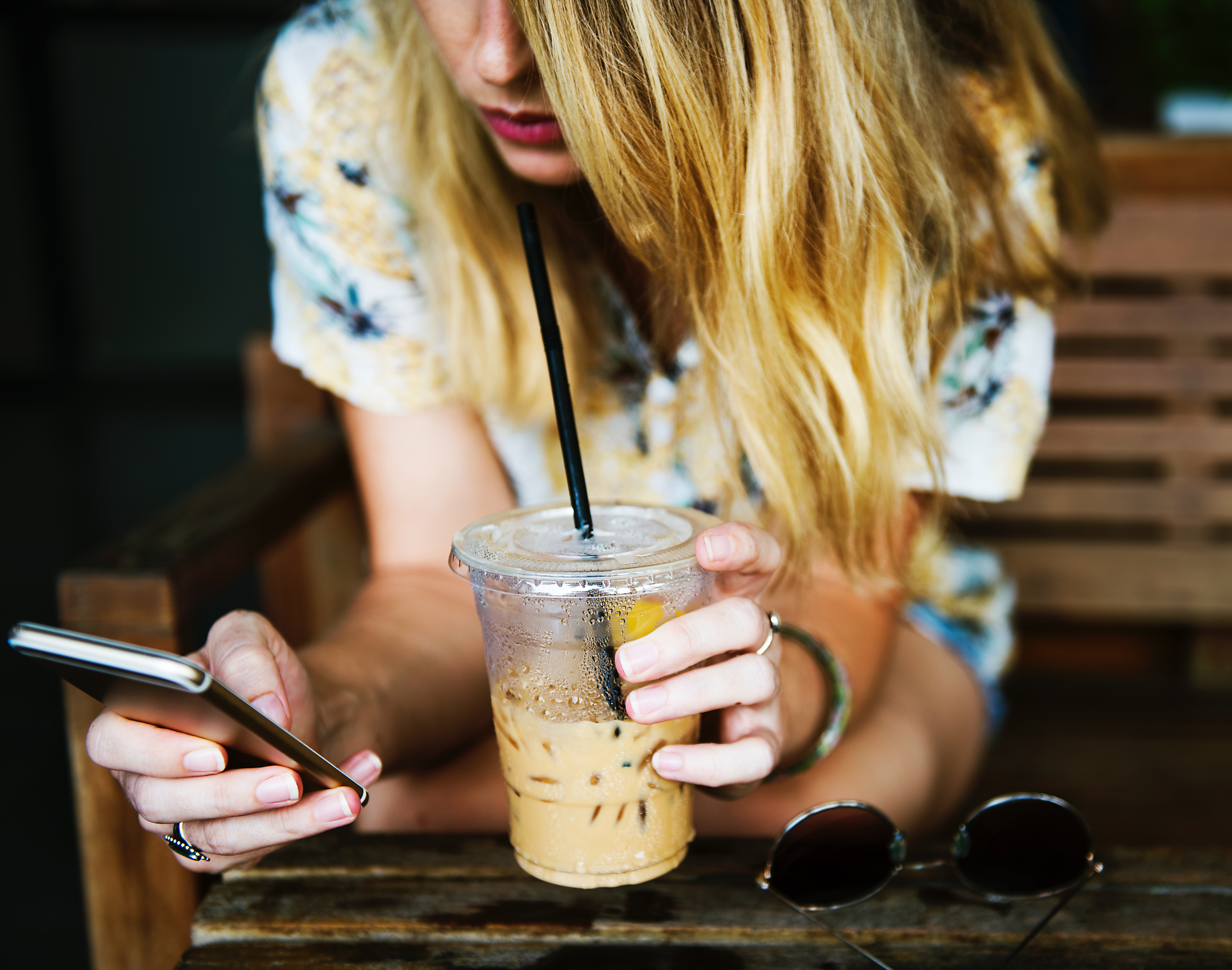 a female playing on her phone with a Starbucks drink beside her