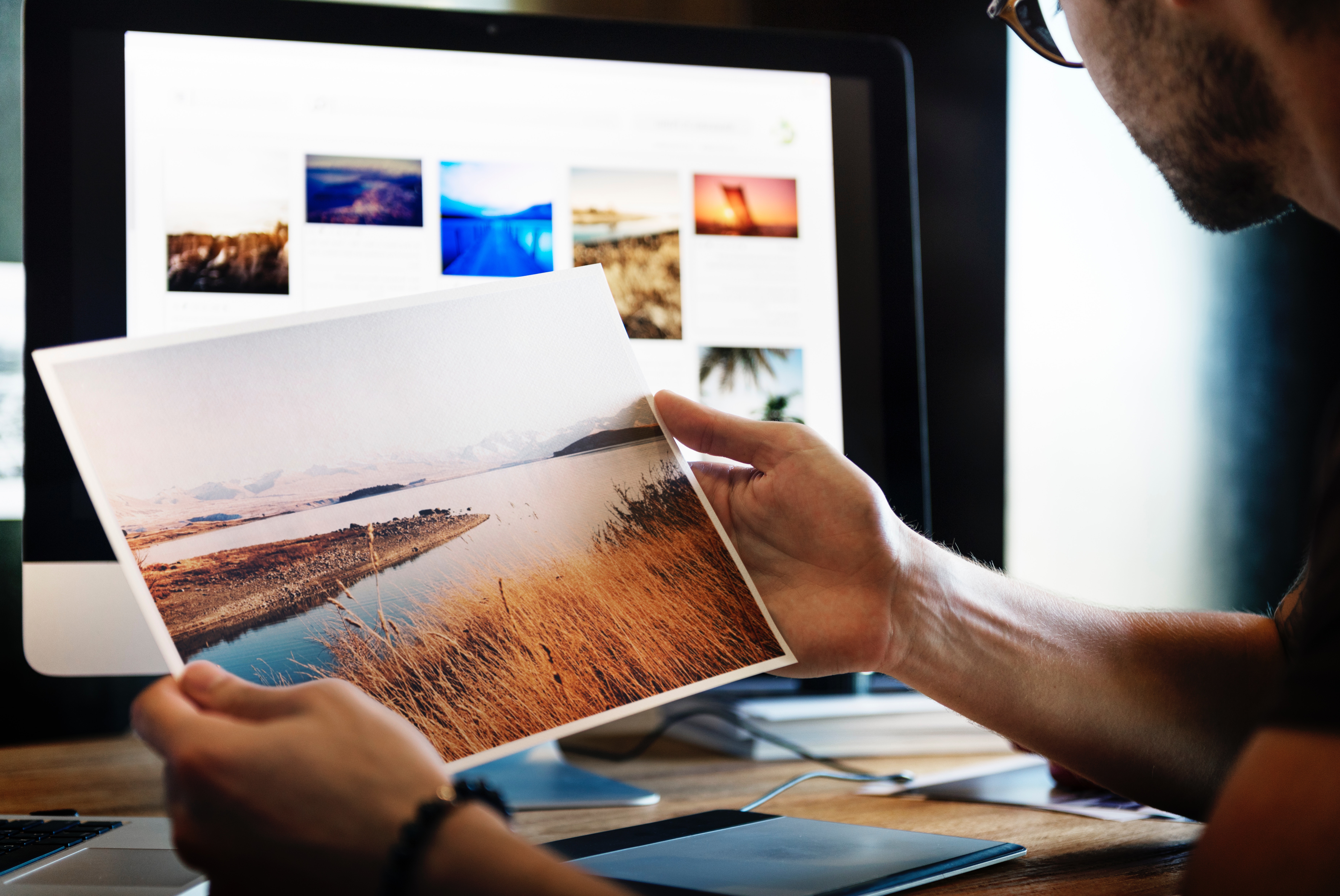 a man holding a nice photo and editing it in a computer as one of his animation jobs