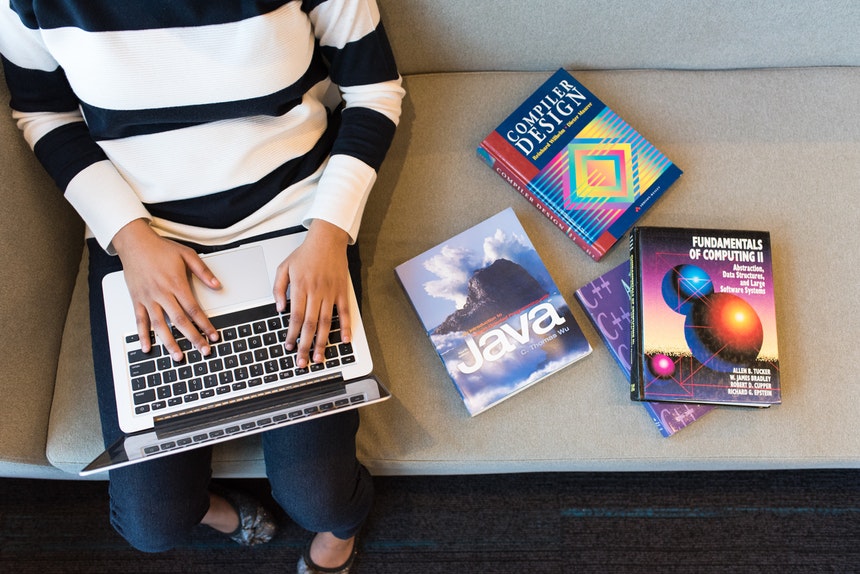 Entertainment and multimedia computing student with MacBook and books