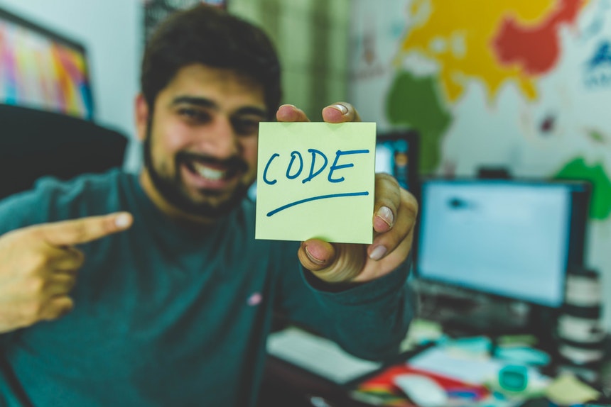 Smiling man holding a sticky note who is happy with Python programming