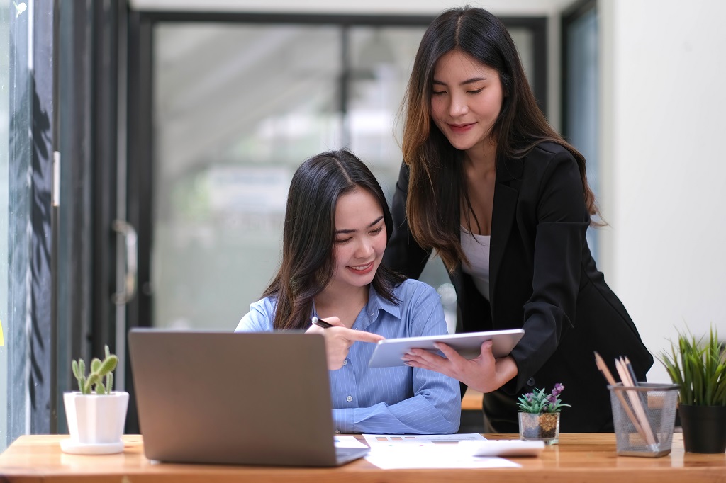 Two young woman discussing about digital marketing tasks