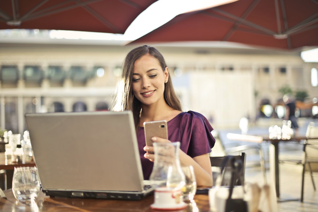 Woman using mobile phone and laptop - apps for millennials